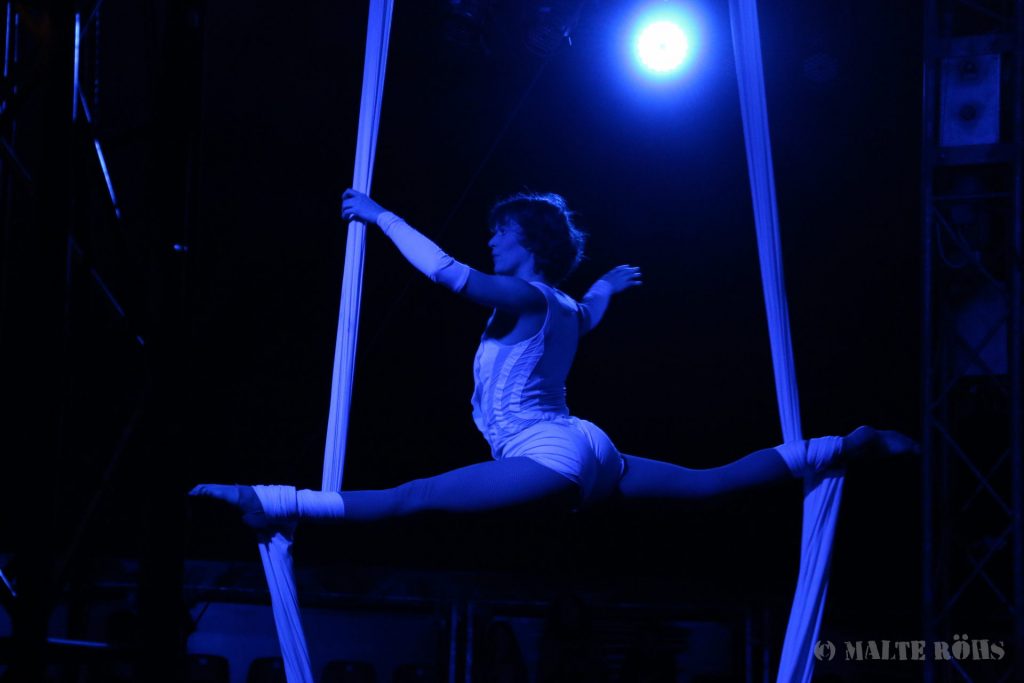 Woman during an amazing aerial silk performance in a show of circus EigenArt